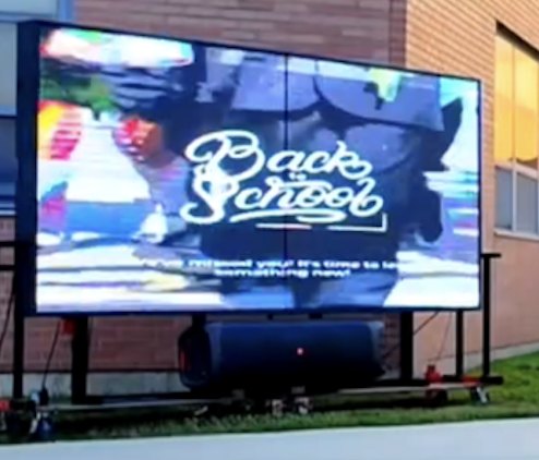 A free-standing Haul Adz LED screen running campaign creative at a back-to-school event